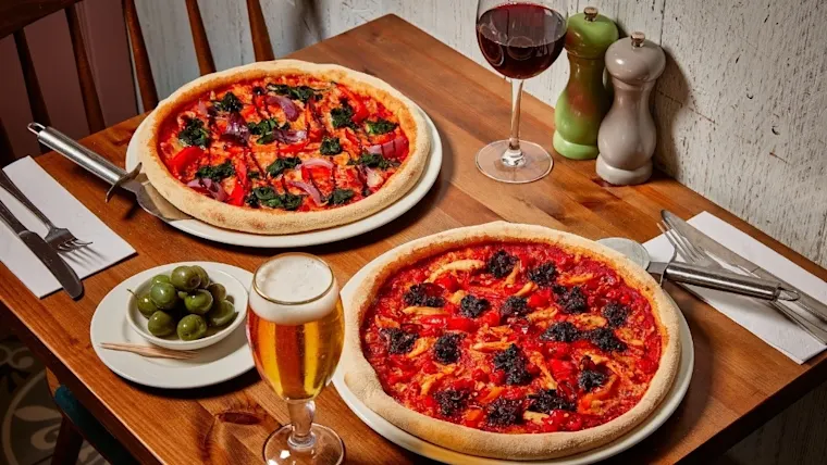 A vegetarian pizza with red peppers, spinach and red onion, and a spicy sausage and chicken pizza.