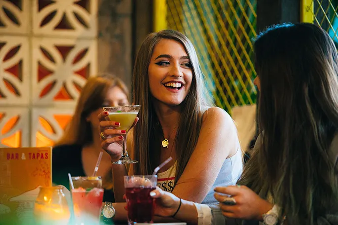 Girls chatting and laughing with cocktails