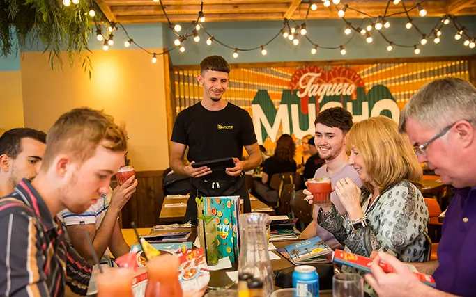 Smiling waiter serving a table of guests