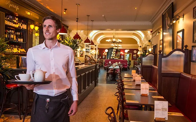 Smiling waiter carrying a tray of tea