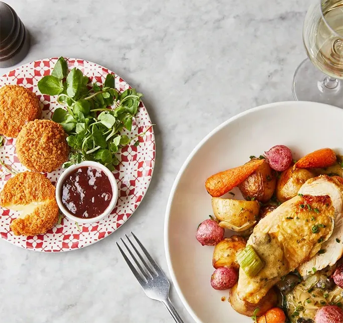 Roast chicken, vegetables and camembert on a marble table with a glass of wine