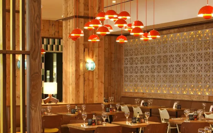 Hanging orange pendant lights, concrete blocks and wood panelling at Las Iguanas Stratford