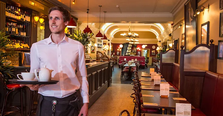 Smiling waiter carrying a tray of tea