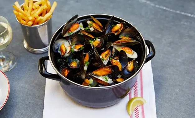Pan of moules with fries and a glass of wine
