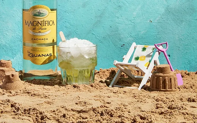 Bottle of Las Iguanas Magnifica Cachaca and a Caipirinha on the beach