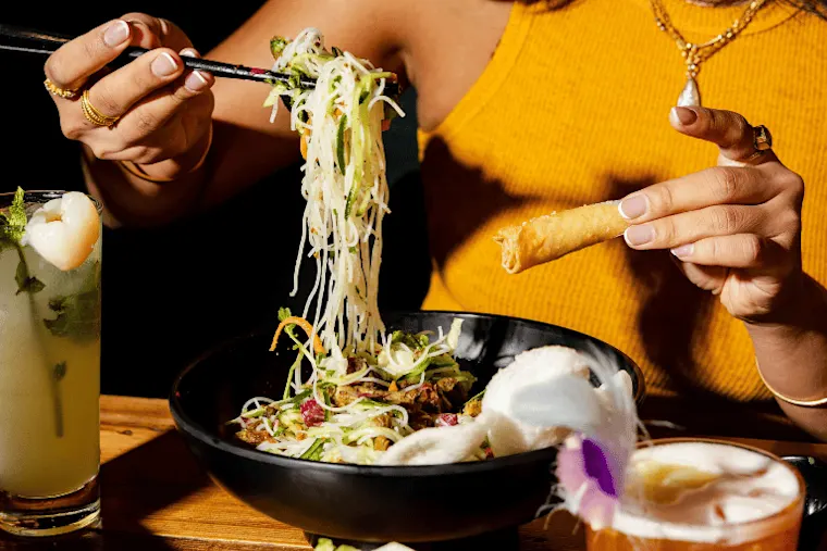 Image of a woman eating a noodle dish
