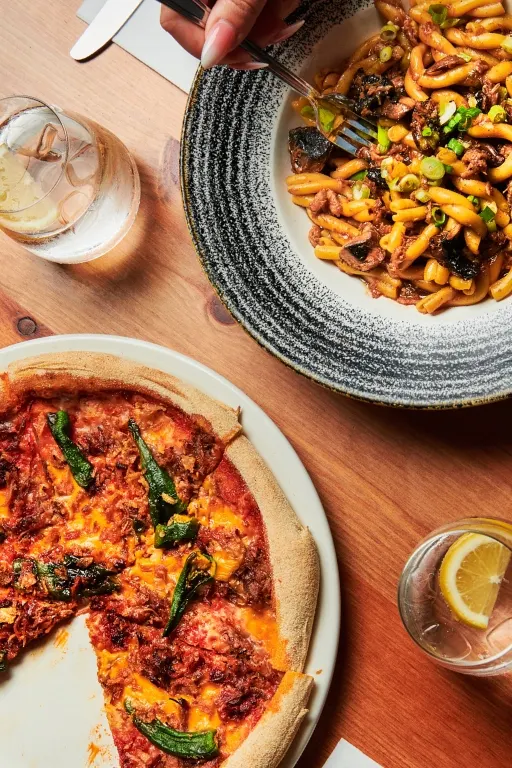 A photo of a spicy pulled beef pizza and pulled duck, spring onion, roasted mushrooms pasta dish.