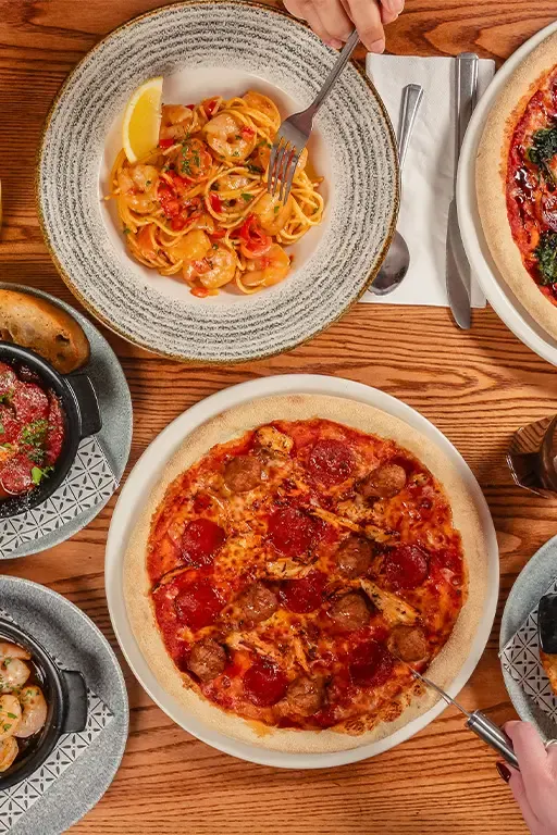 A shared table of pizzas, meatballs and starters set up for a group booking at Bella Italia