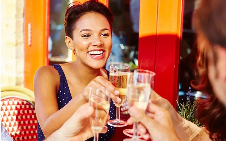 Smiling guest with glass of bubbles sitting on a sunny terrace