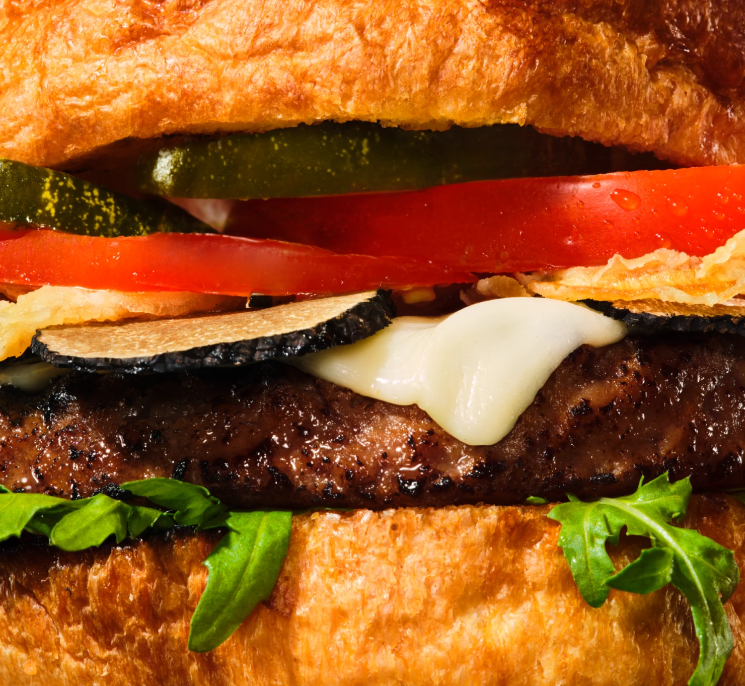 Close up image of Indulgent Burger with lettuce, tomatoes, pickles, and cheese. 