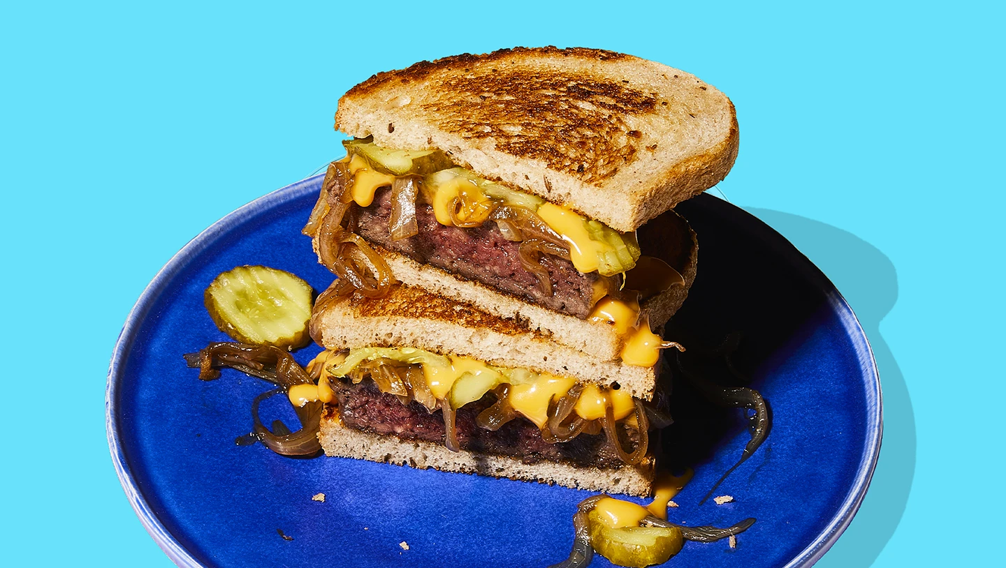 Impossible Burger patty melt with cheese and caramelized onions on blue plate