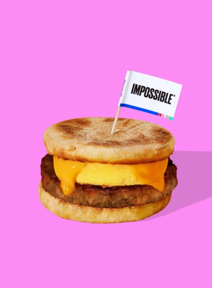 Impossible Sausage Breakfast Sandwich on pink background with Impossible Flag Plant Based Diet Breakfast