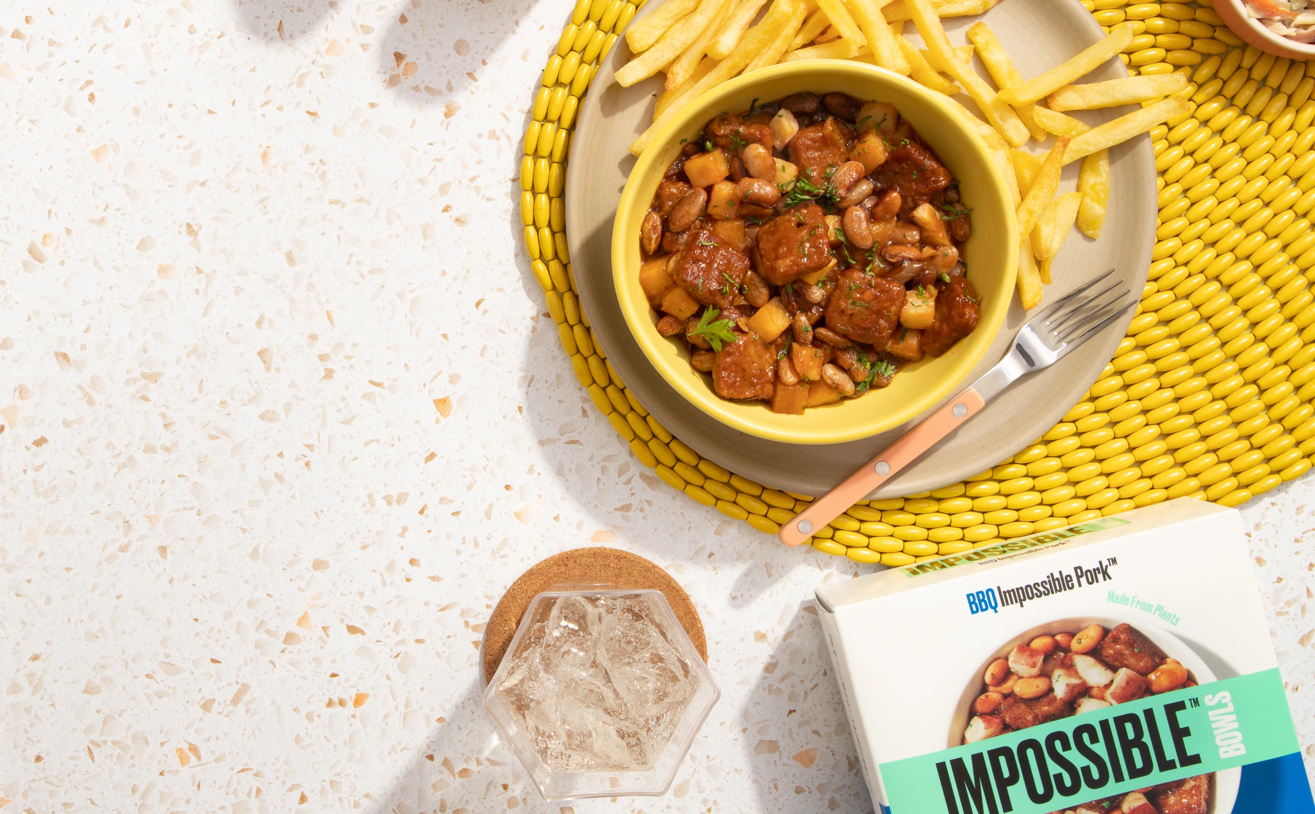 impossible bbq pork package on a speckled counter with a bowl of the meal and french fries