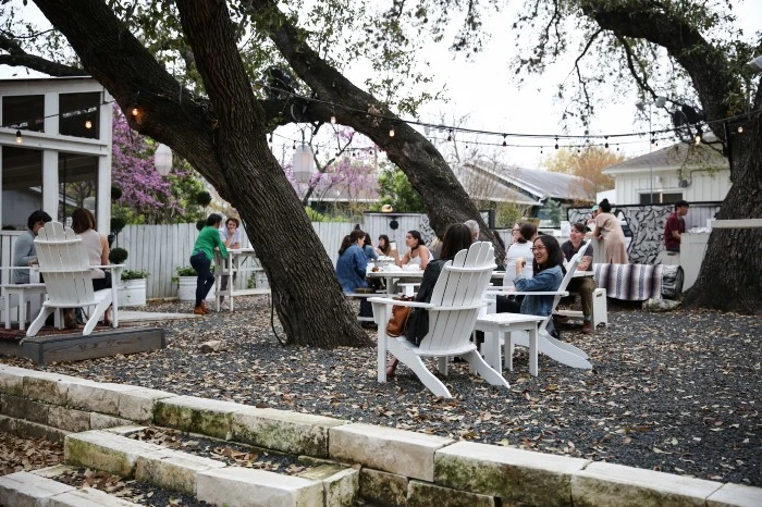People sitting in yard with white chairs and trees with a Sustainable Lifestyle