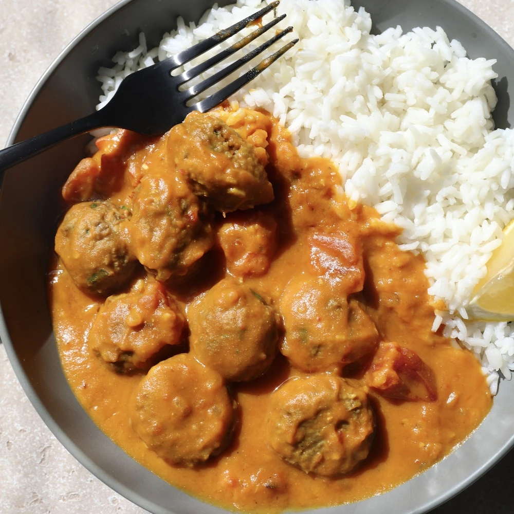 Impossible Beef meatballs with ginger, garlic and cumin in a pumpkin coconut curry sauce over white rice. 