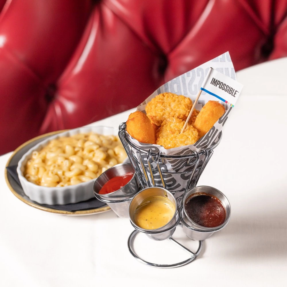 Impossible™ Chicken Nuggets with Agave Mustard Sauce and ketchup dipping sauces with Potato Cauliflower Croquettes, served in a silver serving cup, and mac 'n cheese in the background.