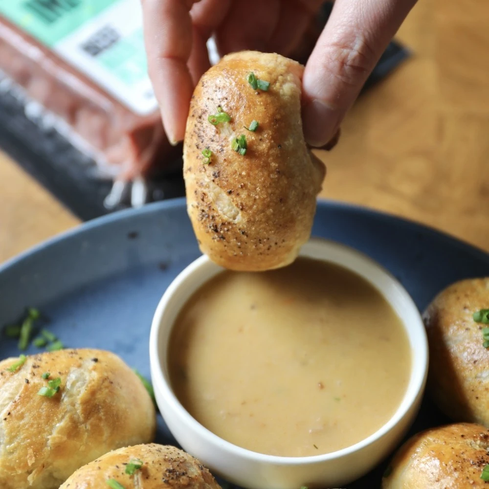 A plate of mini Impossible™ Beef Wellingtons ready to dunk in a rich sauce. 
