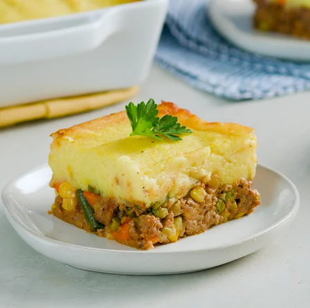 A delicious Impossible Cottage Pie with a filling made from Impossible Beef, carrots, celery, onion, green beans, peas, and corn, and a topping of mashed potatoes. 