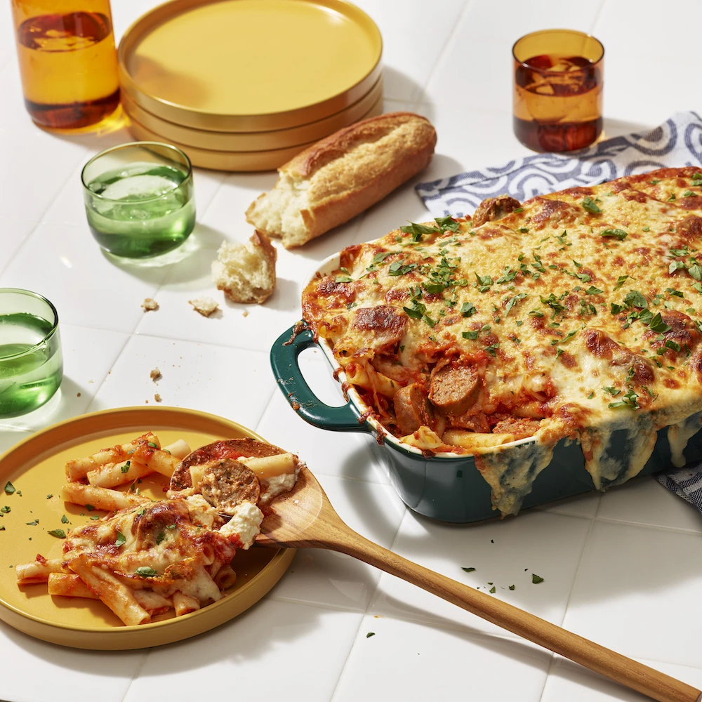 Impossible™ Italian Sausage Links Baked Ziti with gooey cheese and marinara sauce, in baking dish and served on a plate, ready to enjoy. 