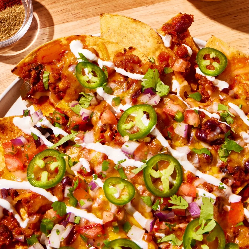 A big plate of Impossible Chili Cheese Nachos featuring Impossible Beef Lite Made From Plants. 