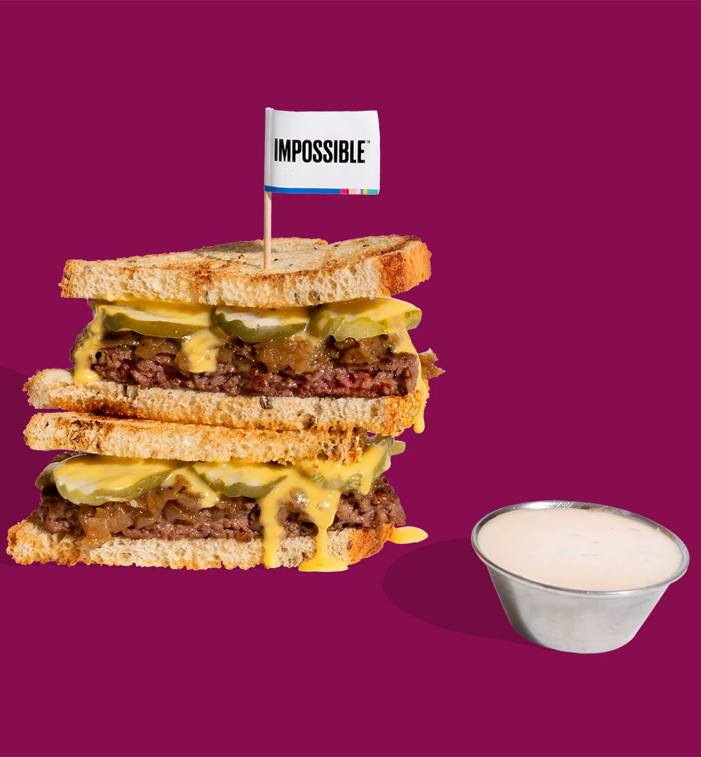 The Impossible Pat-B Melt - Classic Patty Melt with seared ¼ lb Impossible patty, cola-caramelized onions, plant-based cheese whiz, dill pickle chips on thick-cut Texas Toast & a side of Russian dressing dipping sauce