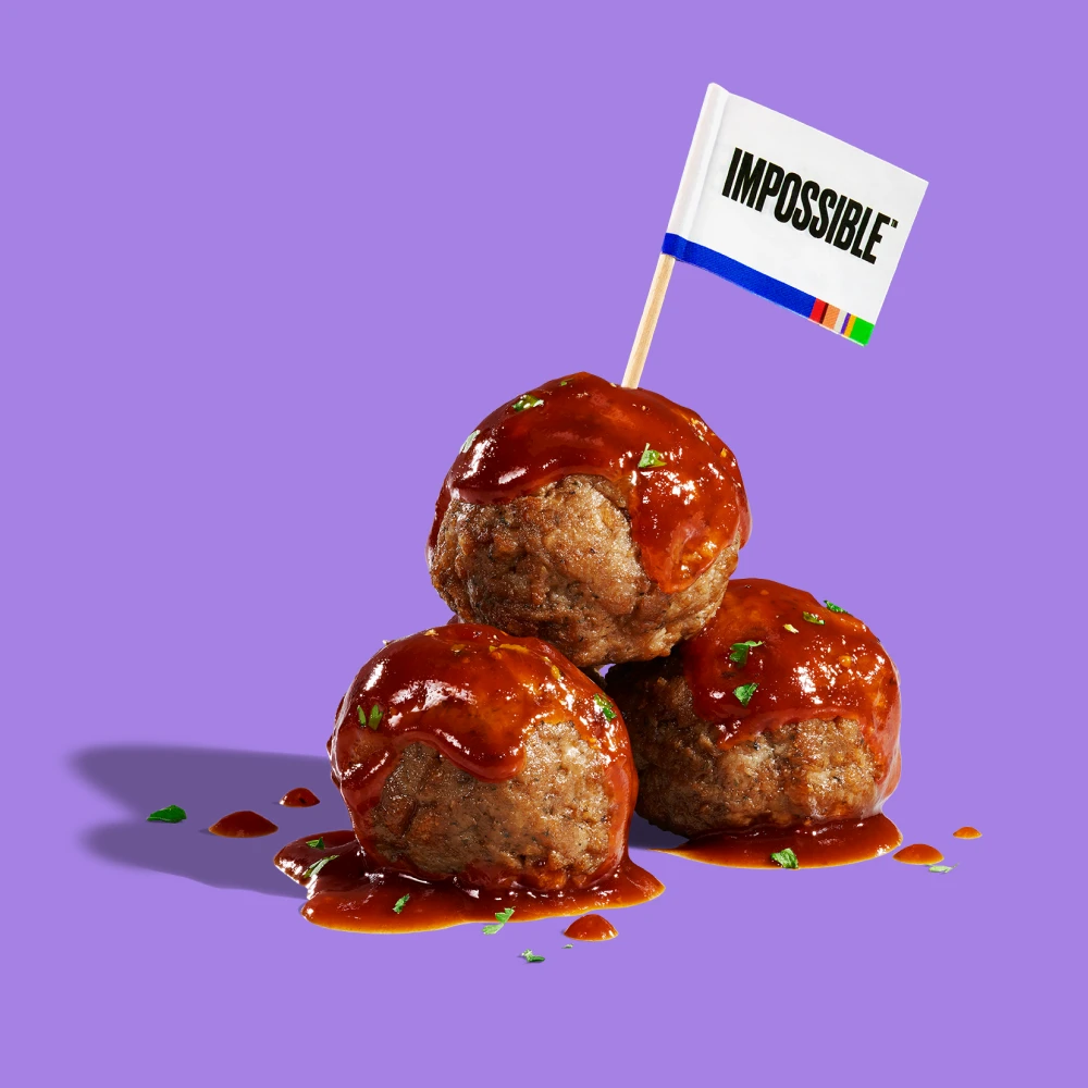 three impossible meatballs with sauce on a purple background
