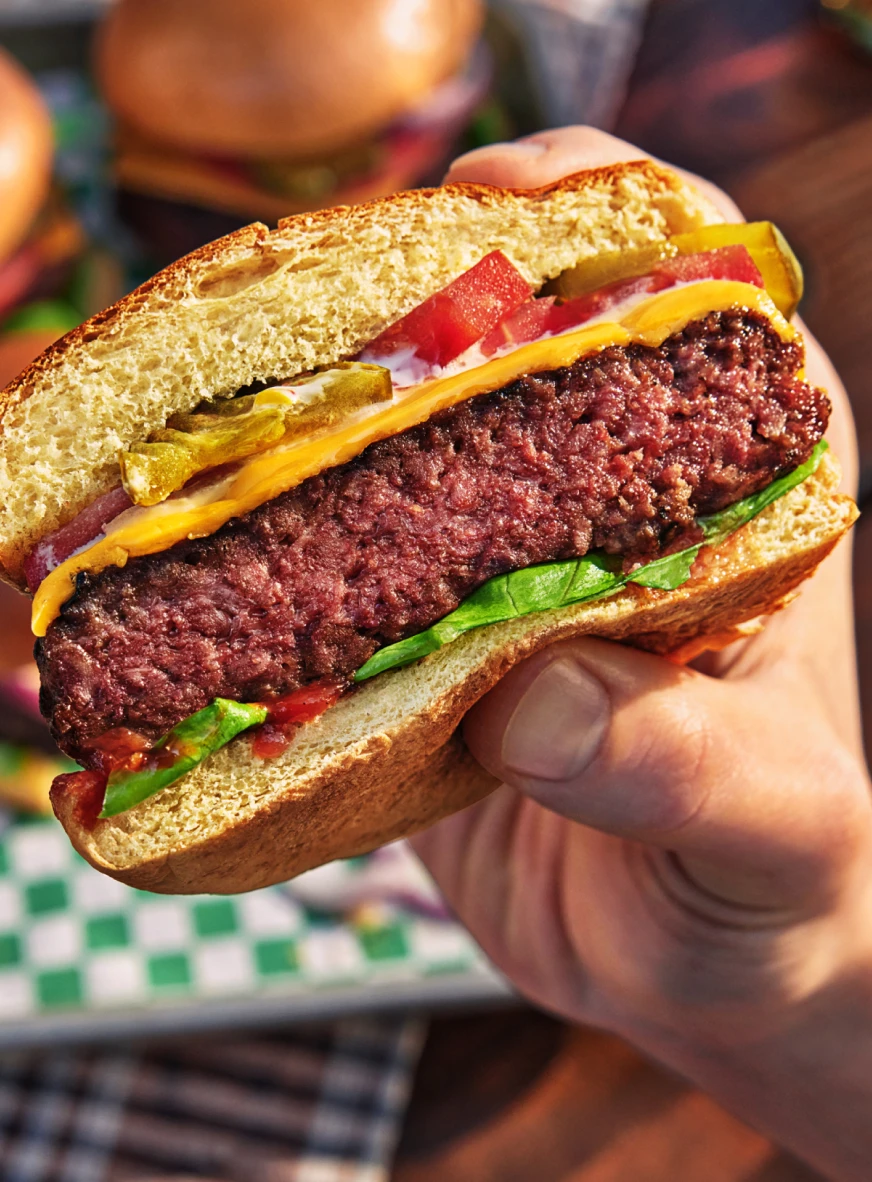 A hand holding an Impossible Burger cut in half