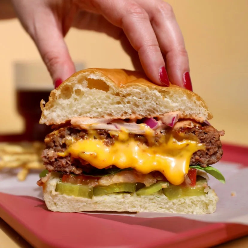 Impossible Juicy Lucy Burger, sliced in half, showing delicious cheese melted in the center of the burger. 