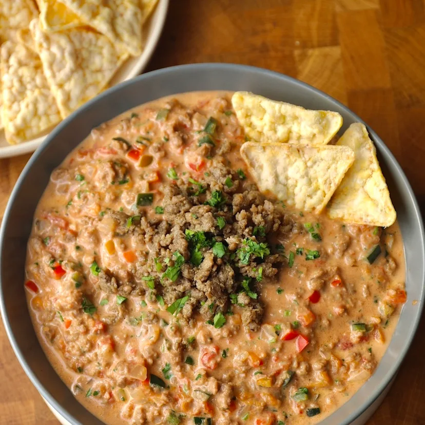 A large bowl of Impossible Beef Chili Con Queso with tortilla chips. 