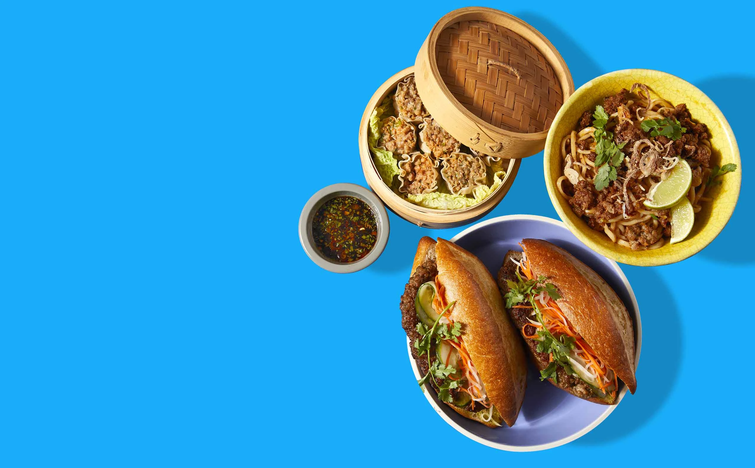 Desktop image of three Impossible Pork dishes: banh mi, dumplings, noodles
