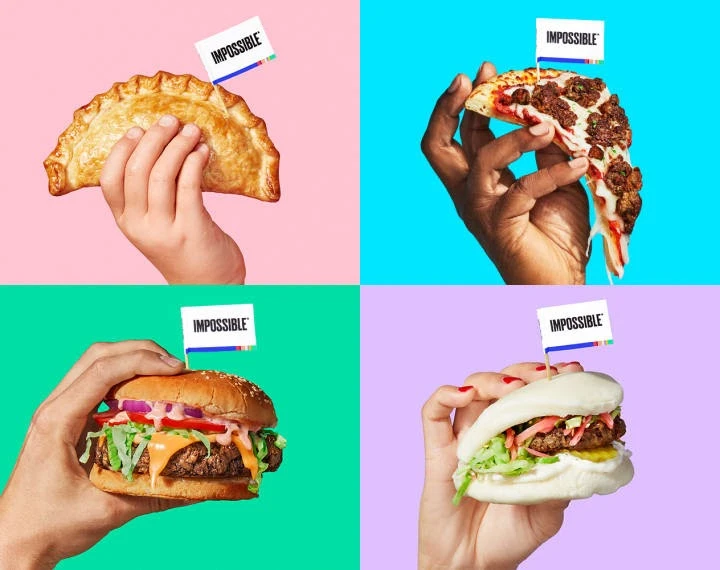 Hands holding Impossible Pizza, Impossible Burger, Impossible Bao, Impossible Empanada