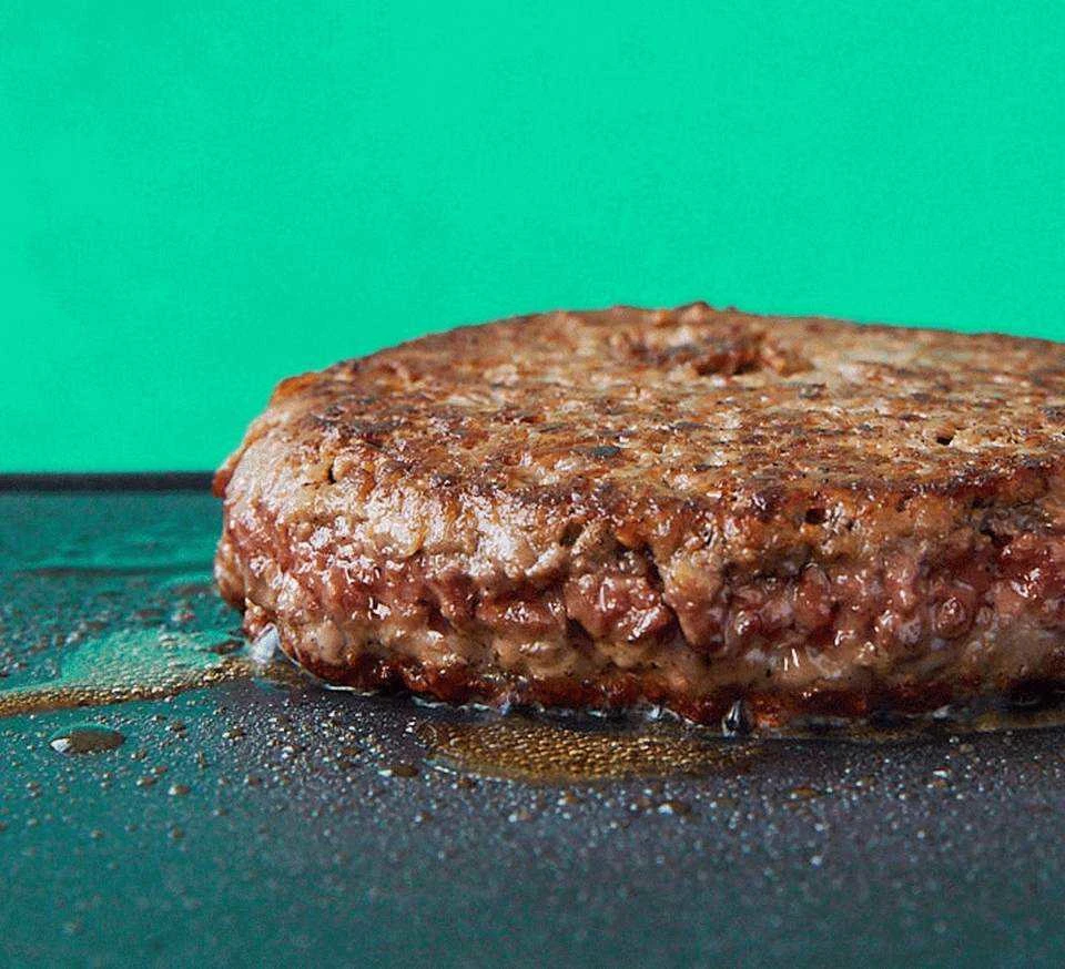 Impossible Burger made from plants on a flat top grill sizzling in bubbling fat