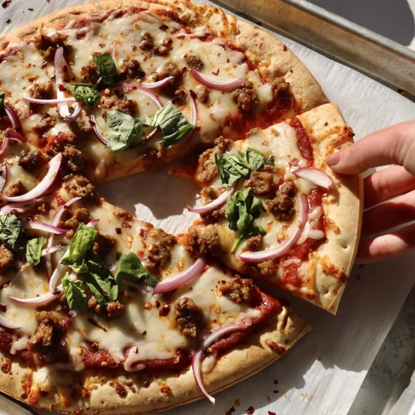 A thick slice of Impossible Spicy Sausage pizza with red onion and basil. 