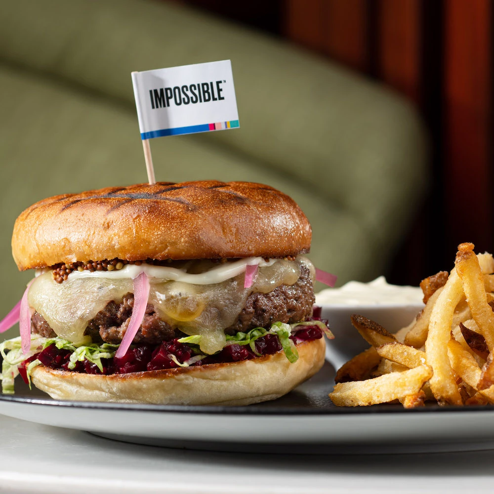 Impossible burger on a plate with fries and a toothpick flag that says "Impossible" 