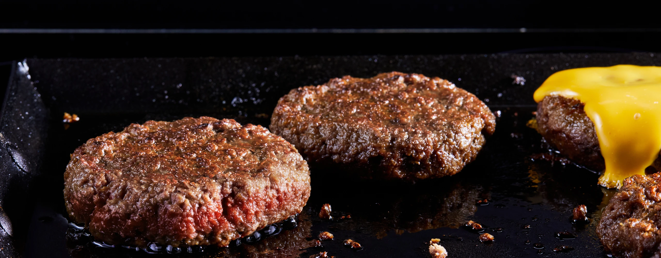 How to cook the new Impossible Burger thumbnail image, Impossible burger patties sizzling on a grill top