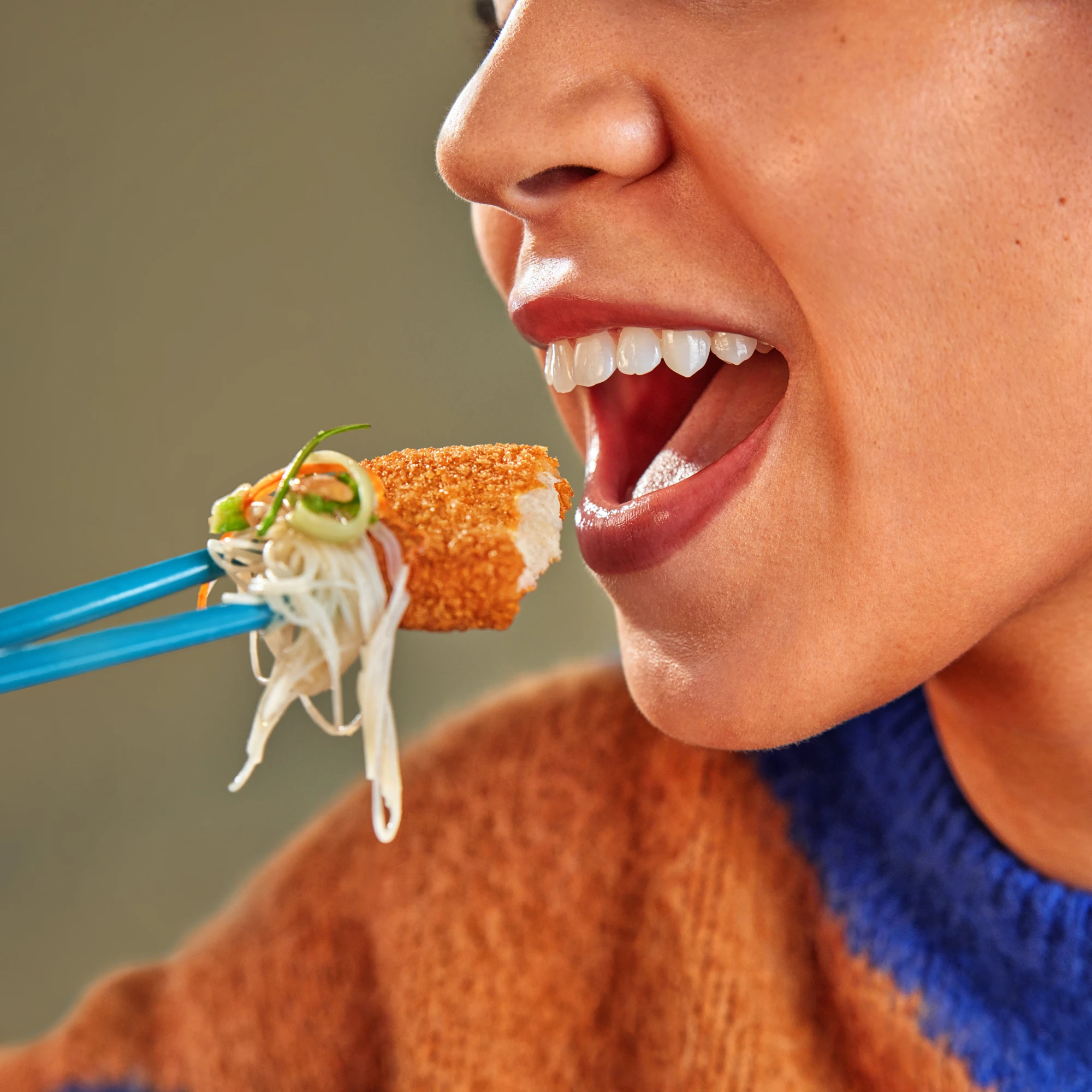 Person eating an Impossible Chicken Tender with chopsticks