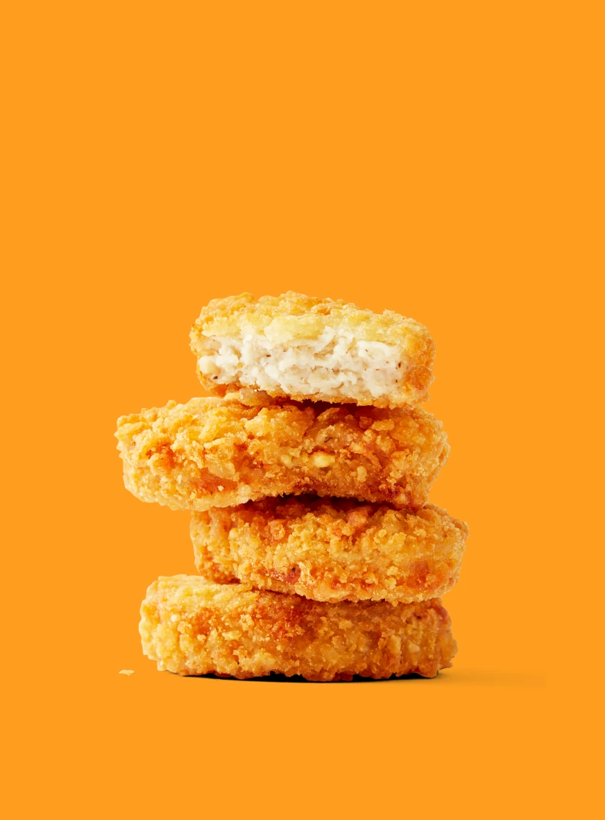 Impossible Chicken Nuggets for foodservice stacked on a yellow background