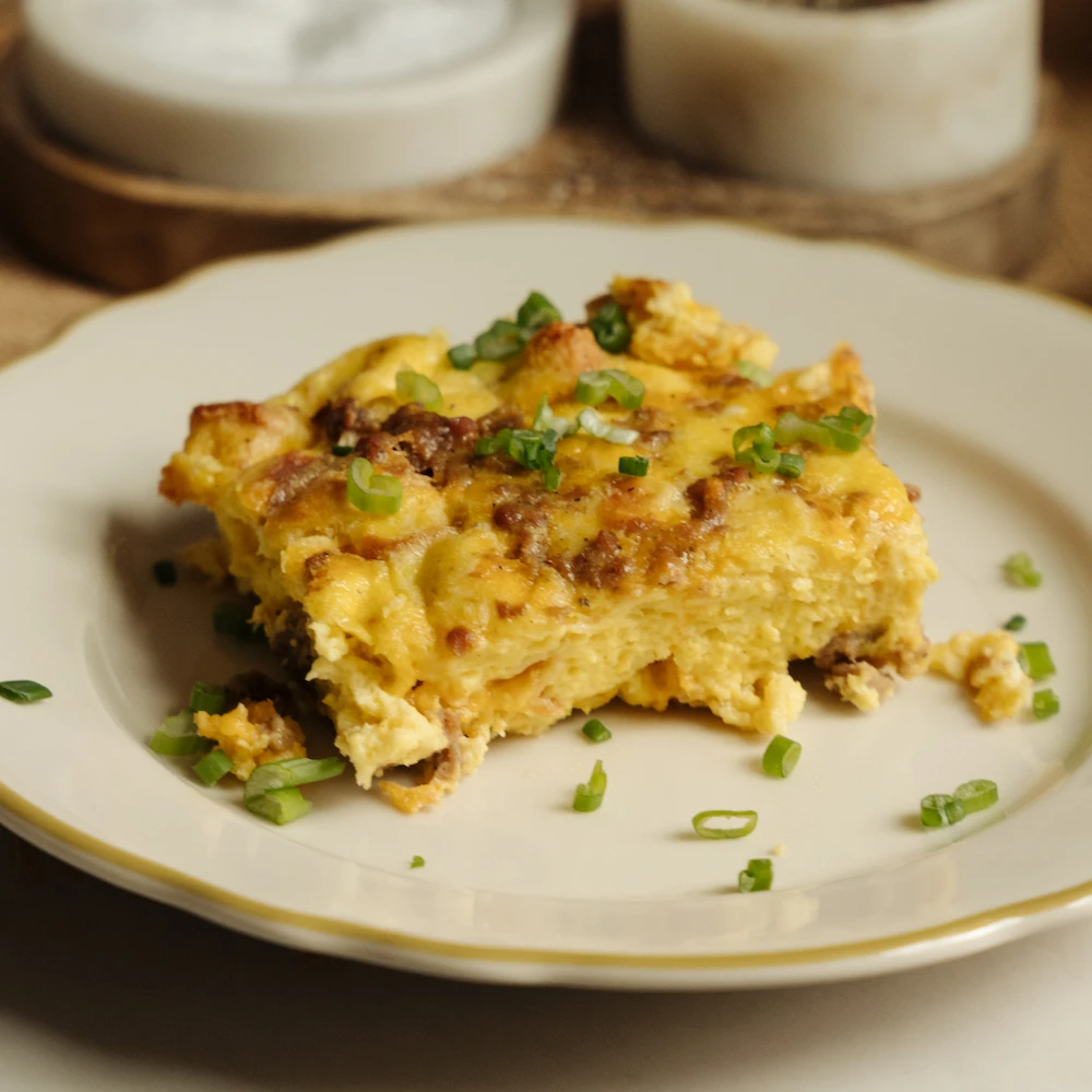 A plate of hot Impossible Sausage Breakfast Casserole garnished with green onions. 