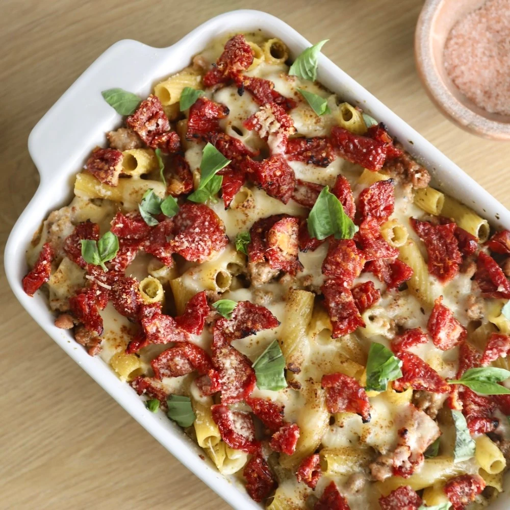 A cheesy, bubbling pesto pasta bake with Impossible Sausage, sun-dried tomatoes, and freshly torn basil.