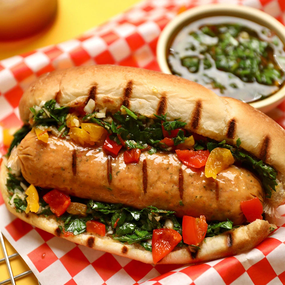 Impossible Grilled Sausage Links topped with chimichurri on a bun. 