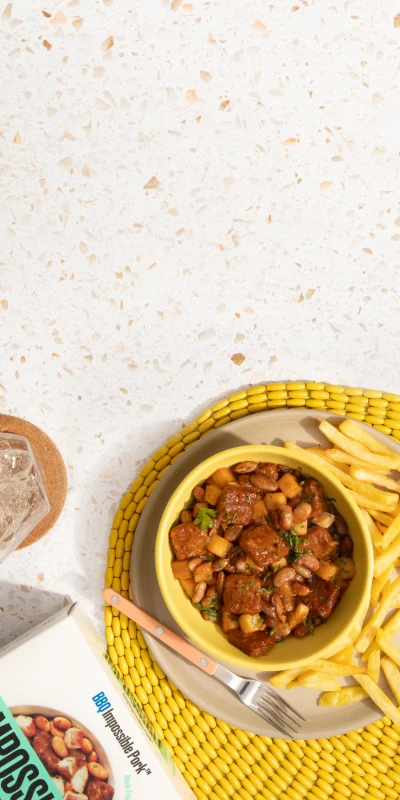 impossible bbq pork package on a speckled counter with a bowl of the meal and french fries