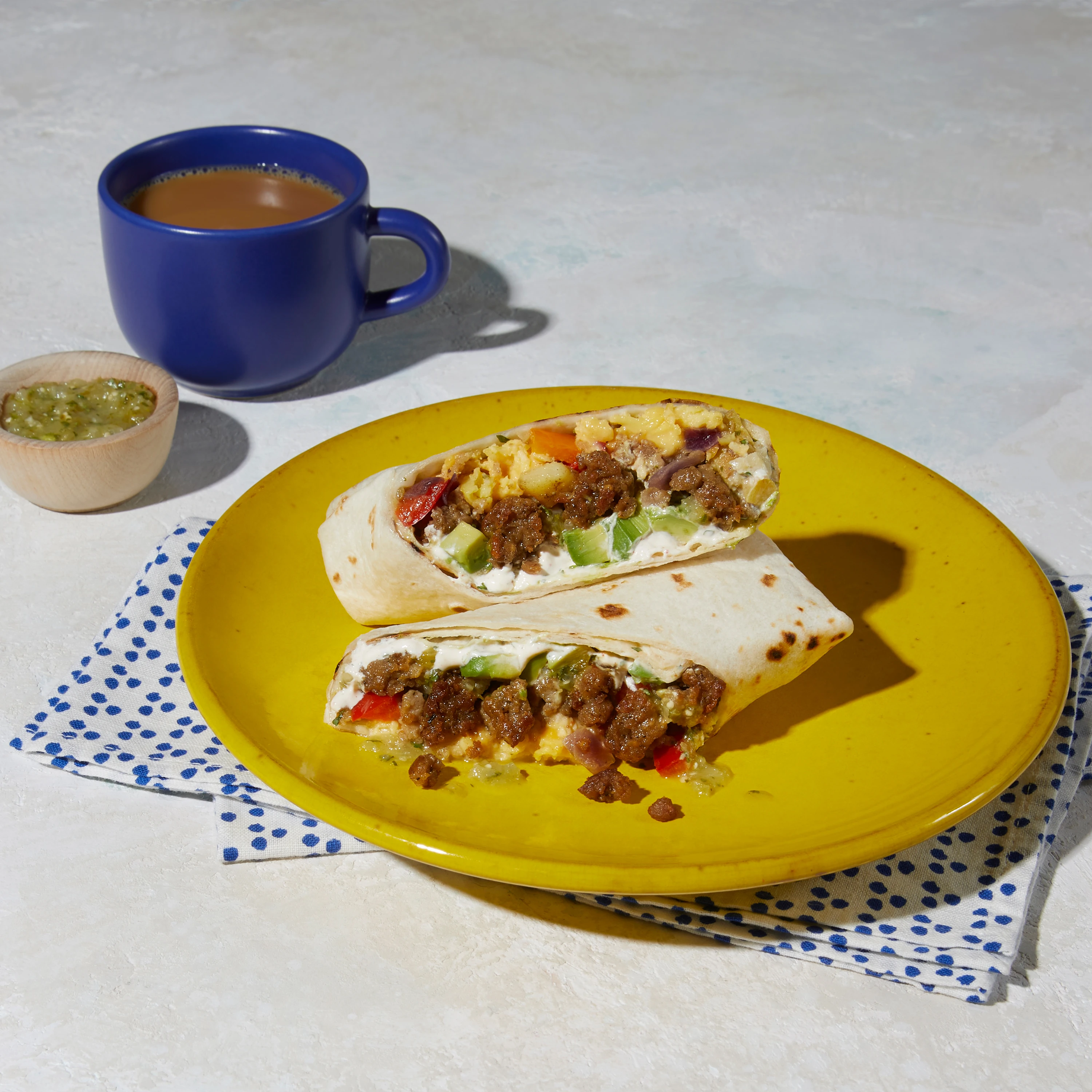 Impossible Sausage breakfast burrito cut in half on a plate 