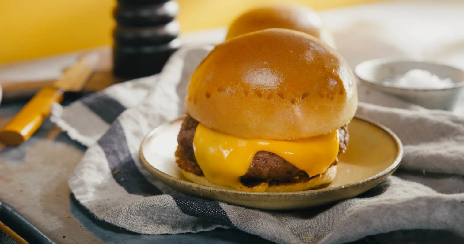 Impossible Cheeseburger being put on a plate with a knife in the background