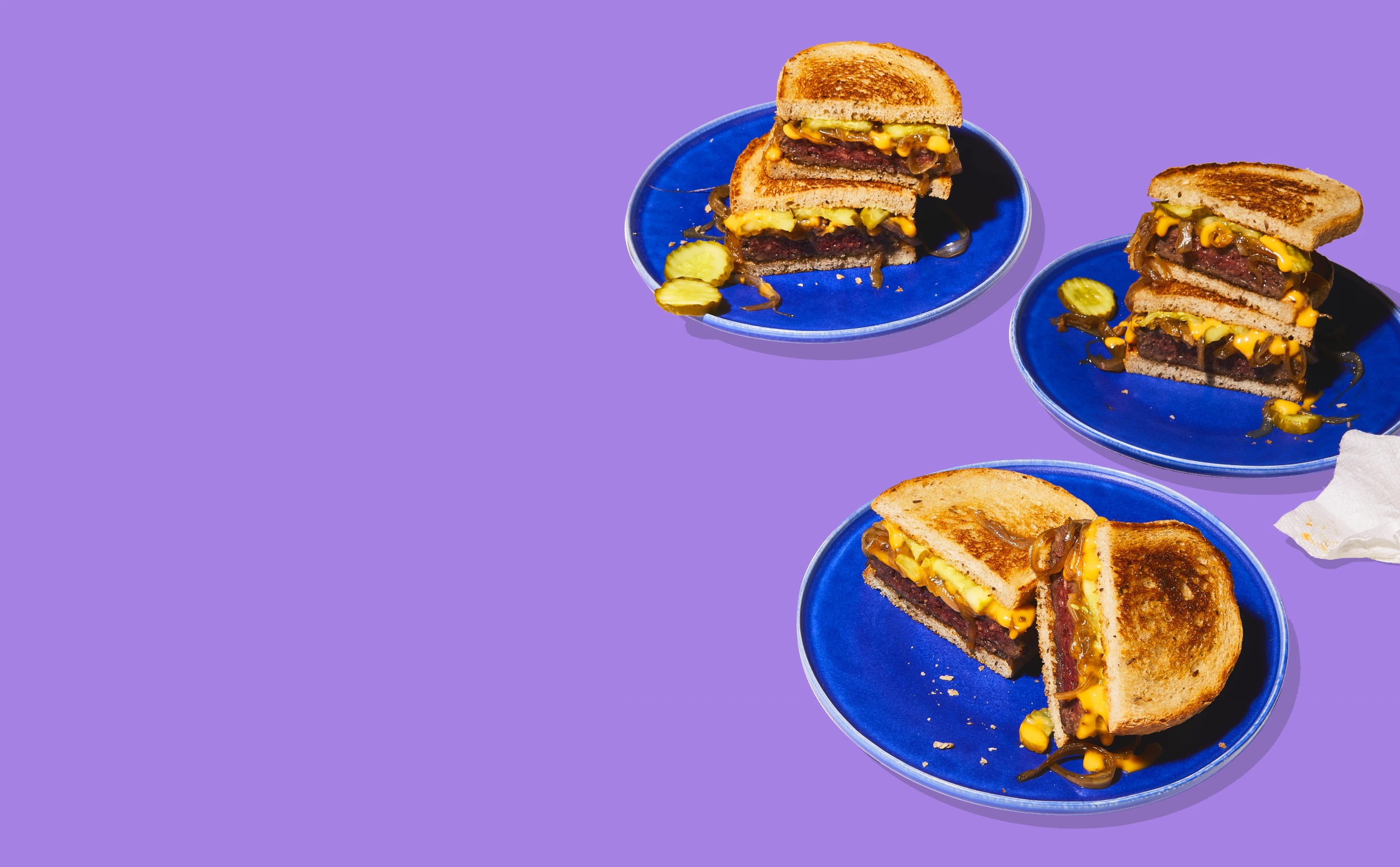 Impossible Burger Patty Melts on plates on purple background