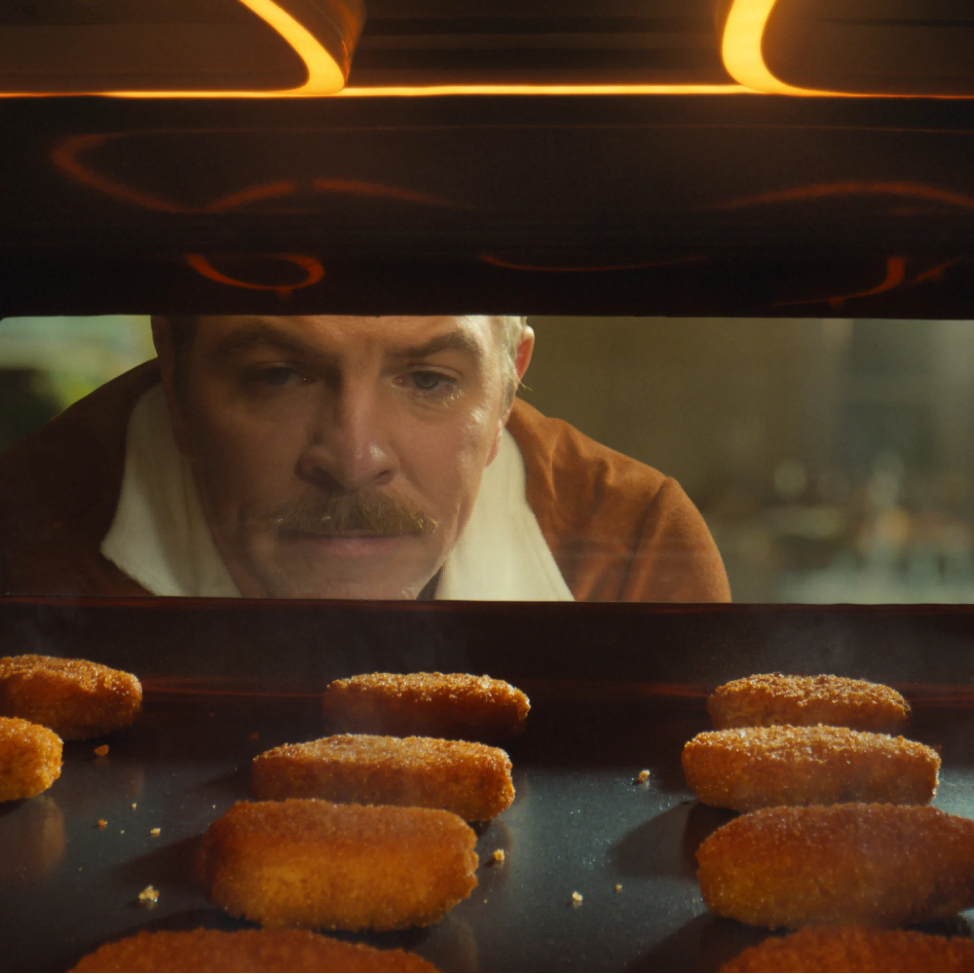 Impossible Chicken Nuggets baking in an oven with a man watching through the window.