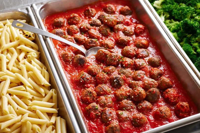 Meatballs in red sauce next to plain pasta and broccoli. 