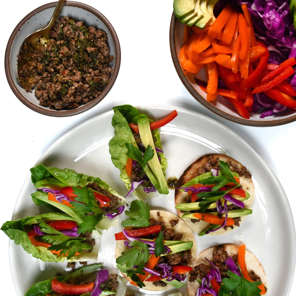 Chimichurri Impossible™ Lettuce Cups made with Haven's Kitchen Herby Chimichurri & Impossible™ Burger, topped with bright veggies and fresh herbs.