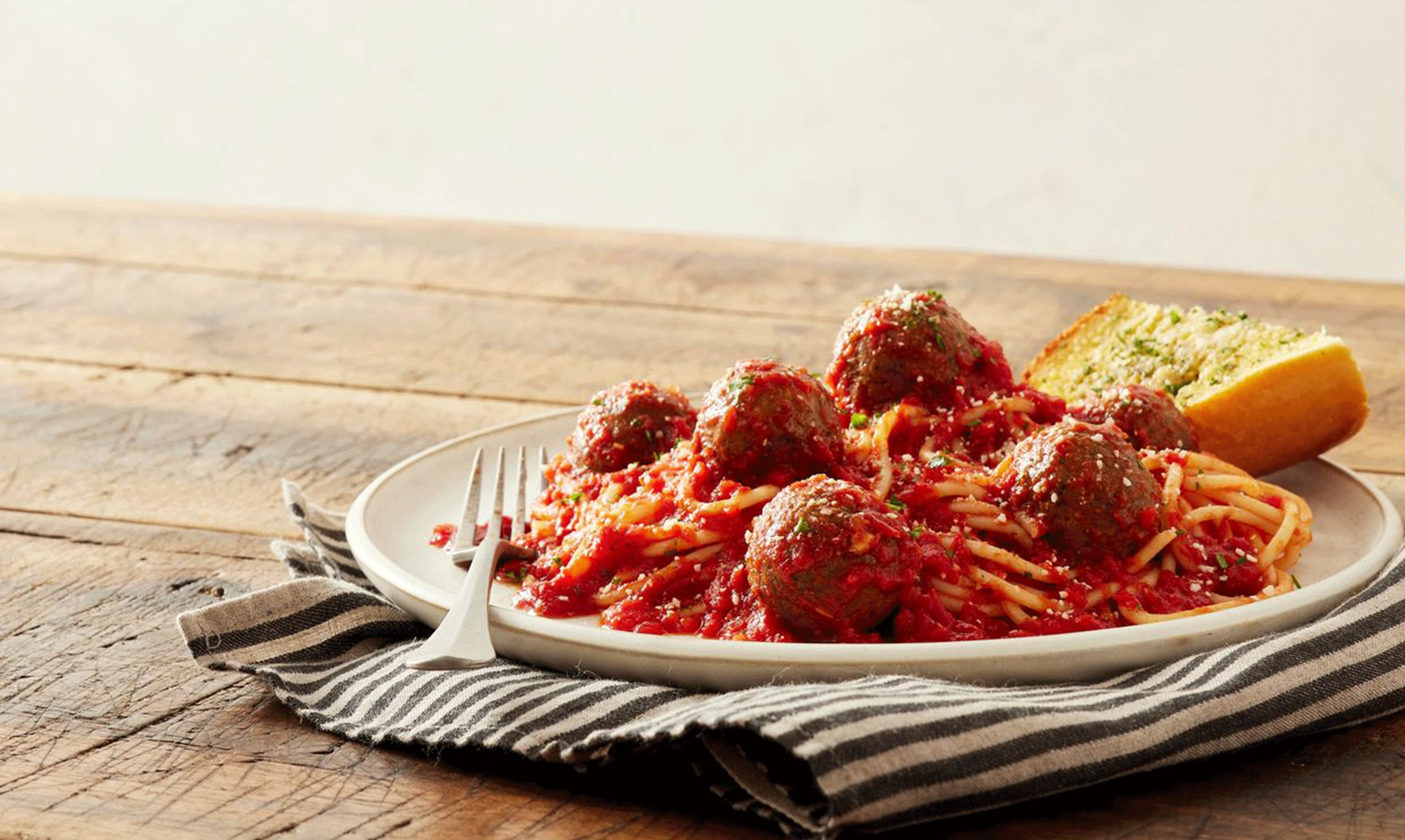 Impossible Meatballs plated with spaghetti and garlic bread. 
