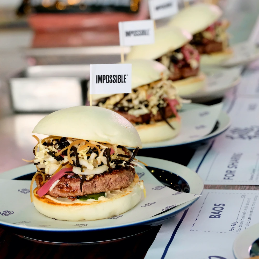 Impossible bao sandwiches lined up on plates next to a menu