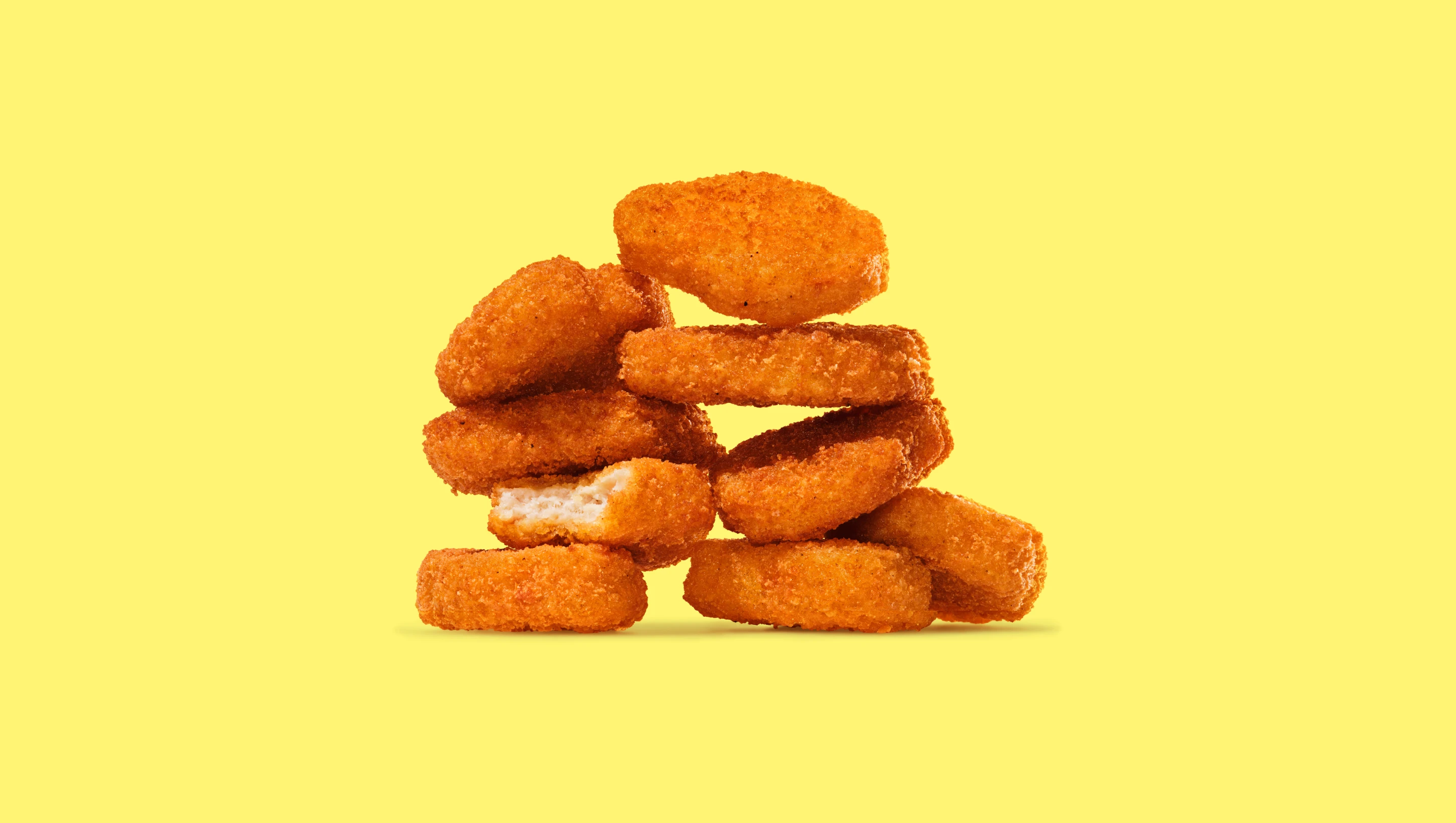 Impossible spicy chicken nuggets in a stack on a yellow background